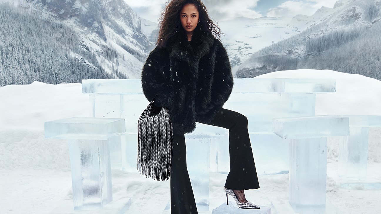 Model seated on ice bar stool with MK fringe bag — Lake Louise mountains in background