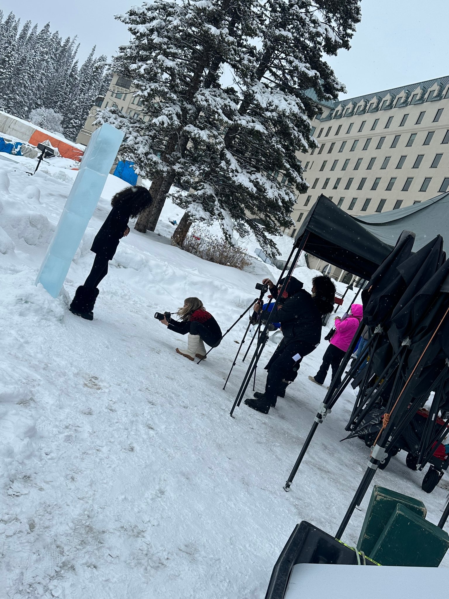 Production crew gathered around the ice bar reviewing the shot — director, DP and talent on set at Lake Louise